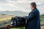 Wesley Deep Pocket Duffle in Raven Black on a fence rail beside a man overlooking the hills