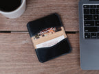 Slim Business Card Holder in Black with cards inside, on a wooden desk beside a laptop and coffee