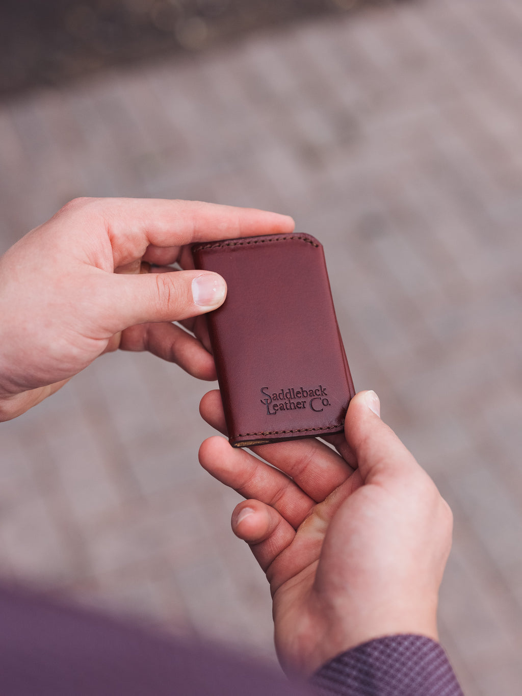 Slim Business Card Holder in Oxblood, held in hands showing the embossed logo