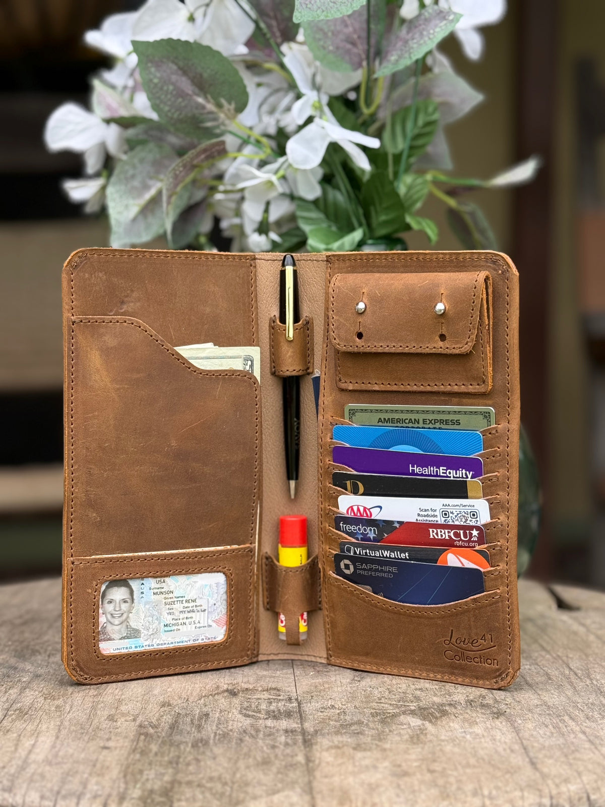 New Big Wallet in Tobacco standing open on a wood table filled with cards, cash, pen and ID