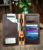 New Big Wallet in Dark Coffee Brown open on a wood table filled with cards, cash, pen and passport
