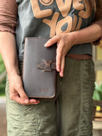 New Big Wallet in Dark Coffee Brown held closed upright at the waist, strap closure facing out