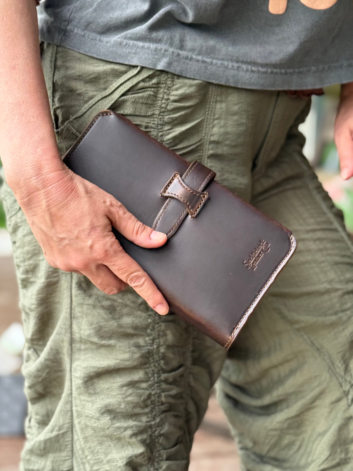 New Big Wallet in Dark Coffee Brown held in hand against olive cargo pants