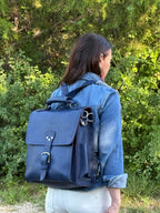 Saddleback Club Membership Paul Revere Leather Messenger Bag Backpack in Blue, worn as a backpack by a woman outdoors