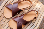 Pair of Jesus Sandals in Chestnut on a weathered wooden deck, top view