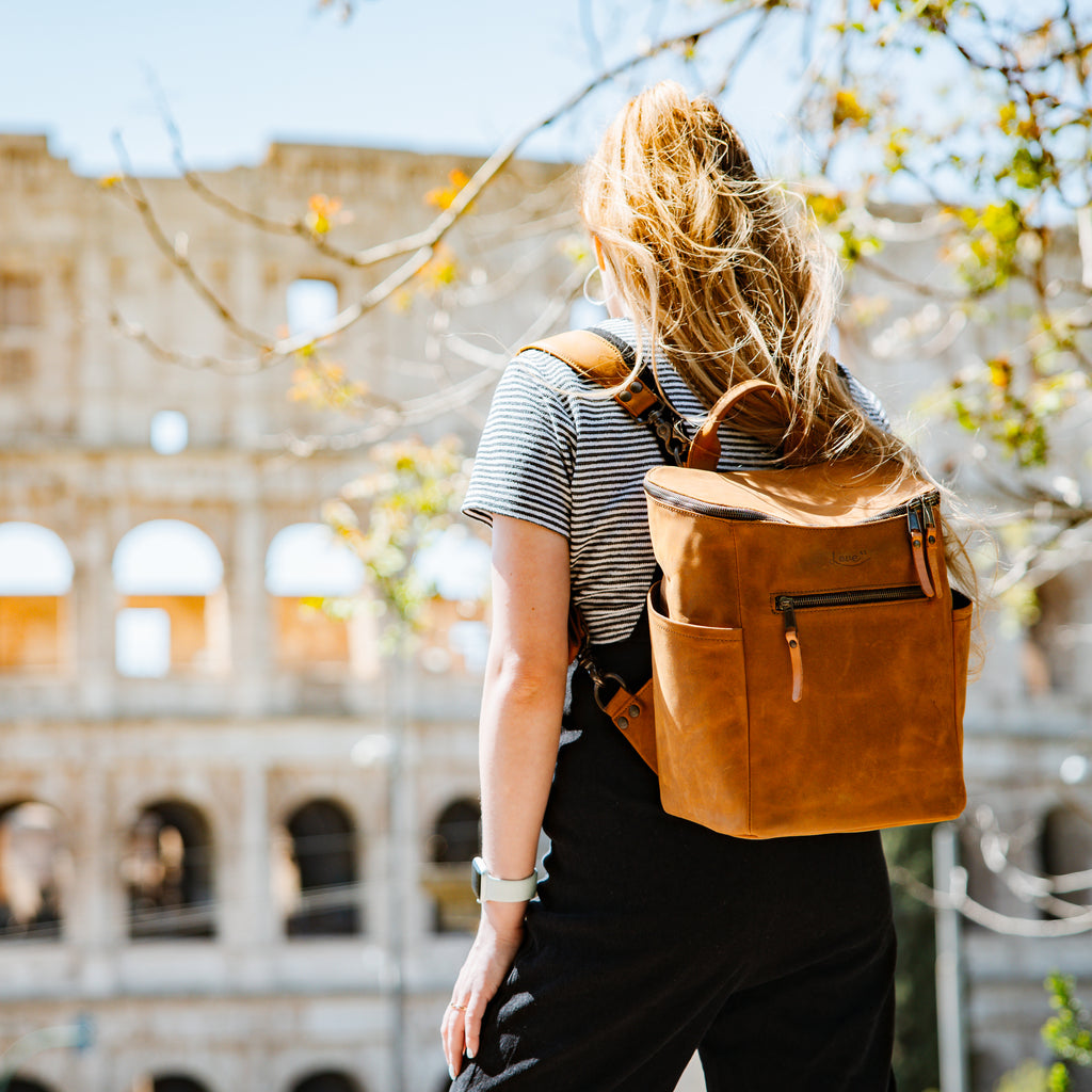 All in One Backpack Medium in Tobacco worn by a woman in front of the Colosseum in Rome