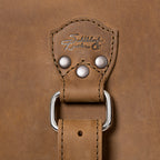 27" Adolescent Beast Duffle Bag in Tobacco, close-up of the embossed logo tab, rivets and D-ring strap