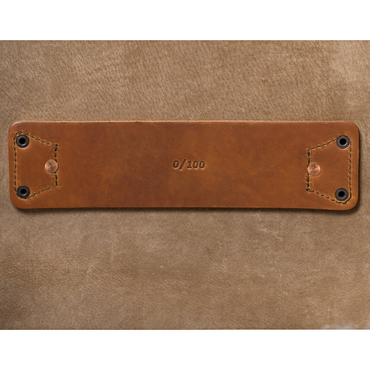 27" Adolescent Beast Duffle Bag in Tobacco, close-up of the stamped leather tab riveted to the suede lining