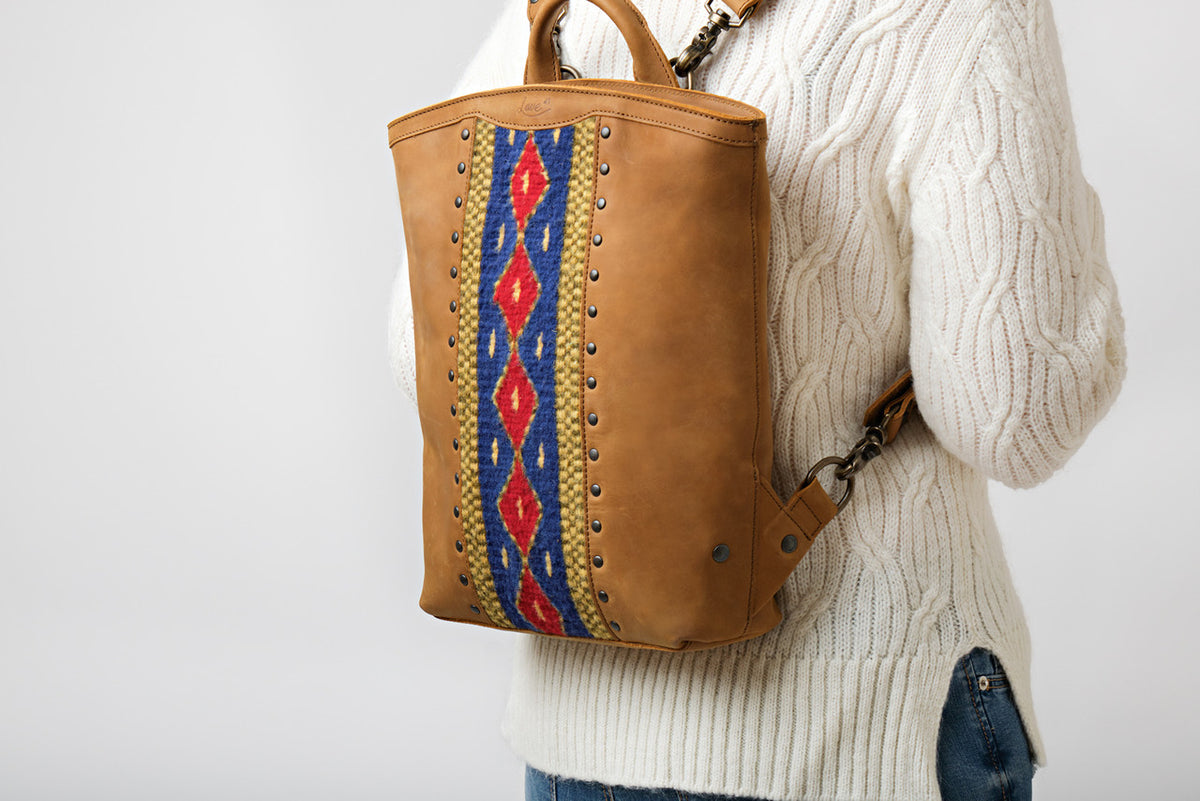 Lanita Leather Backpack in Tobacco, worn on the back by a model in a cream cable-knit sweater