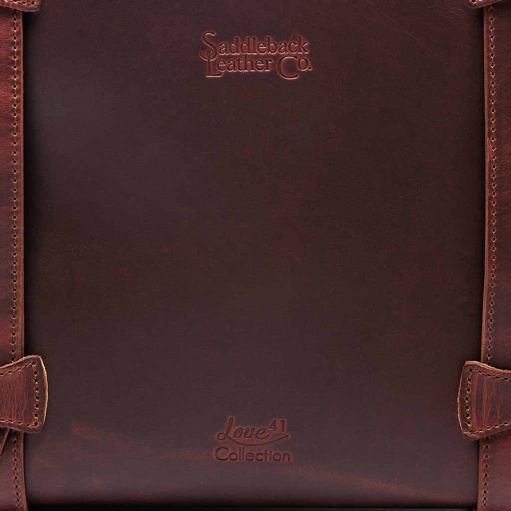 Original Tote in Chestnut, close-up of the leather panel with embossed logos and stitched strap loops