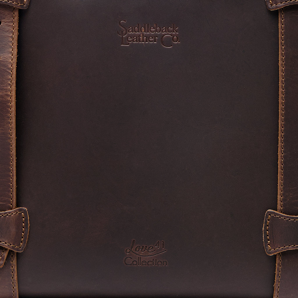 Original Tote in Dark Coffee Brown, close-up of the leather panel with embossed logos and stitched strap loops