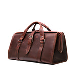 Leather Range and Tool Bag in Chestnut, angled front view with top handles, buckle strap and side frame opening
