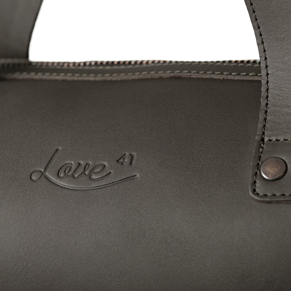 Simple Overnight Leather Duffle Bag in Black, close-up of the embossed Love 41 logo and riveted handle