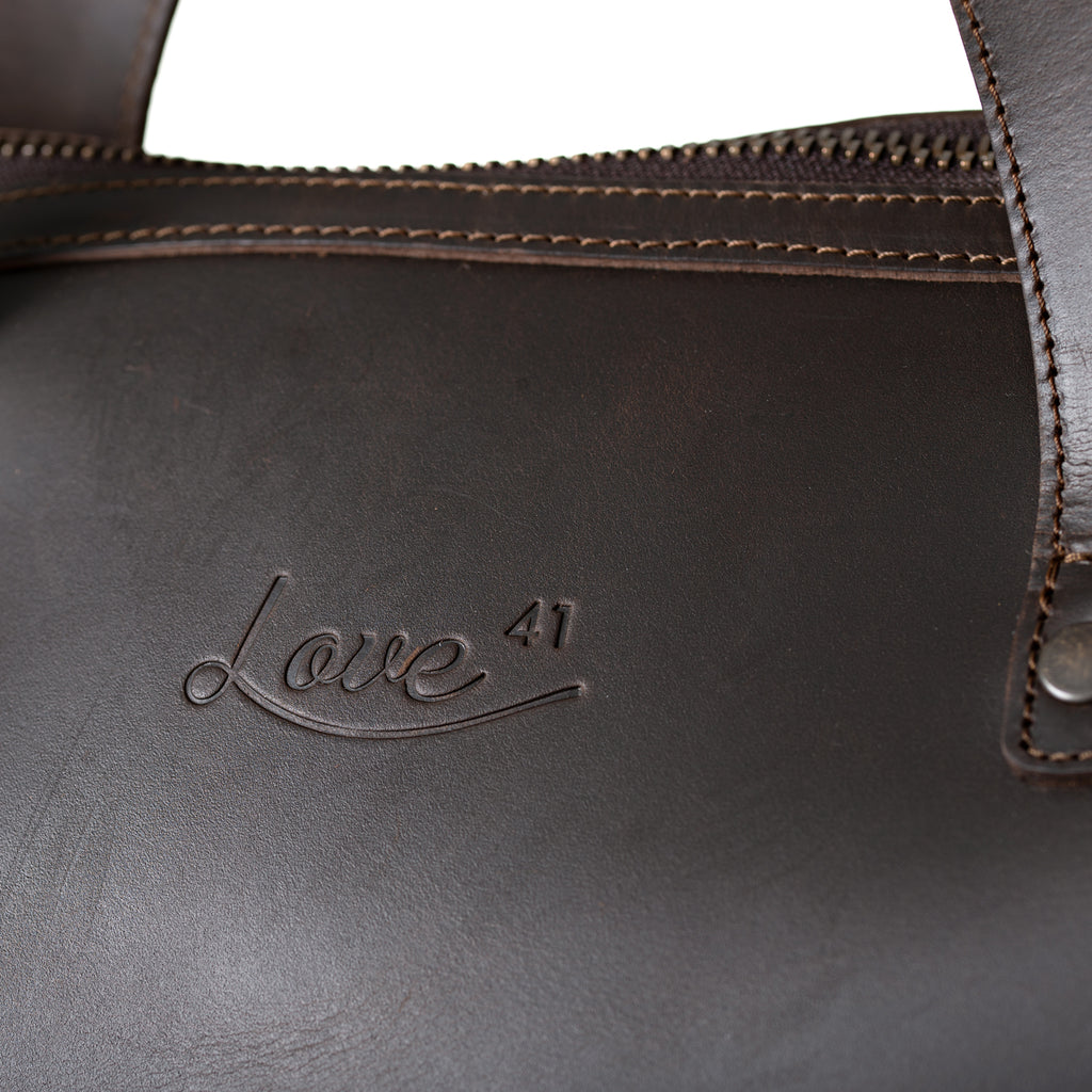 Simple Overnight Leather Duffle Bag in Dark Coffee Brown, close-up of the embossed Love 41 logo and riveted handle
