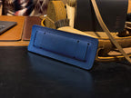 Freedom Collection Extra Shoulder Pad in Blue, underside shown on a desk beside a tan leather bag