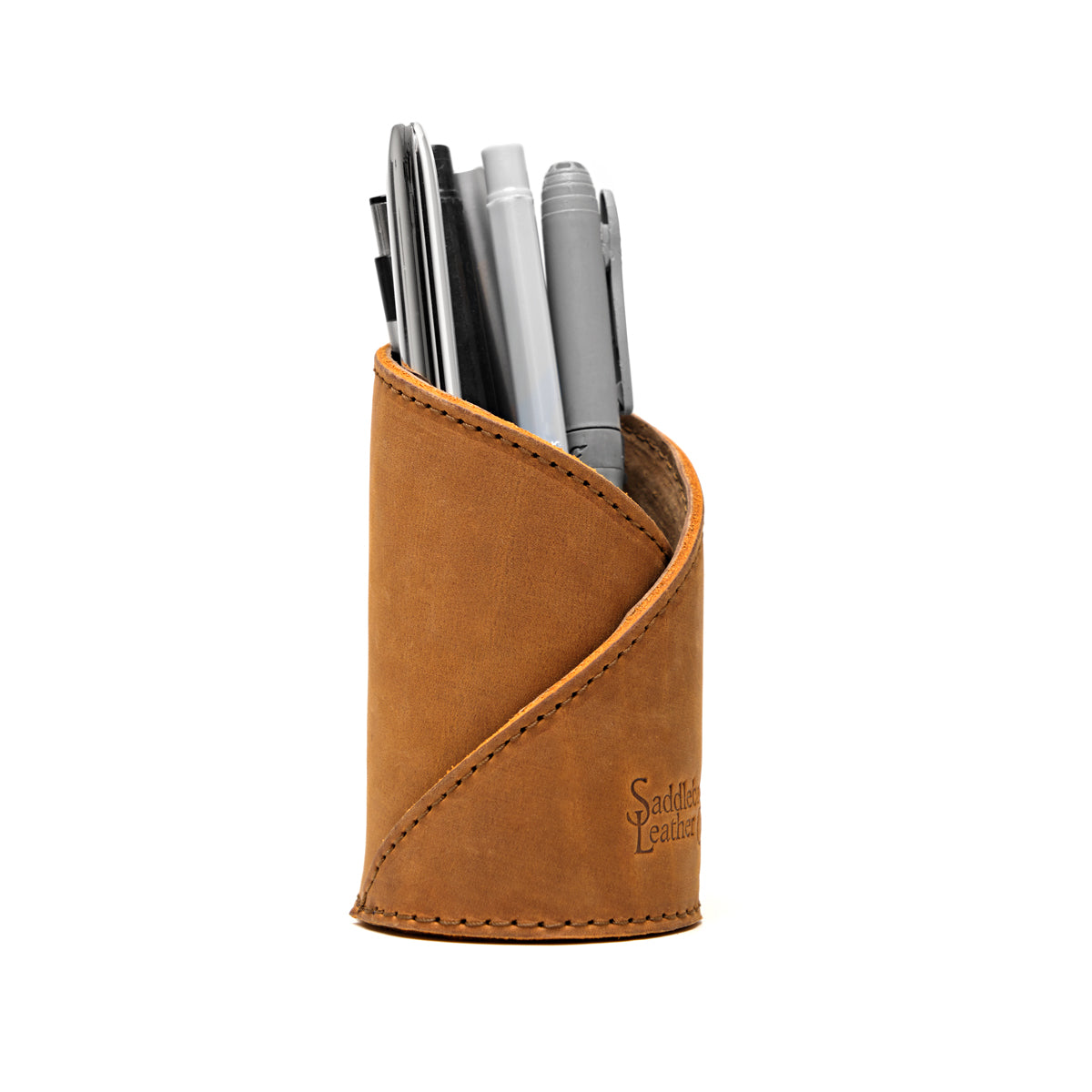 Pen Cup in Tobacco leather, front view showing the diagonal stitched wrap and embossed logo, holding pens