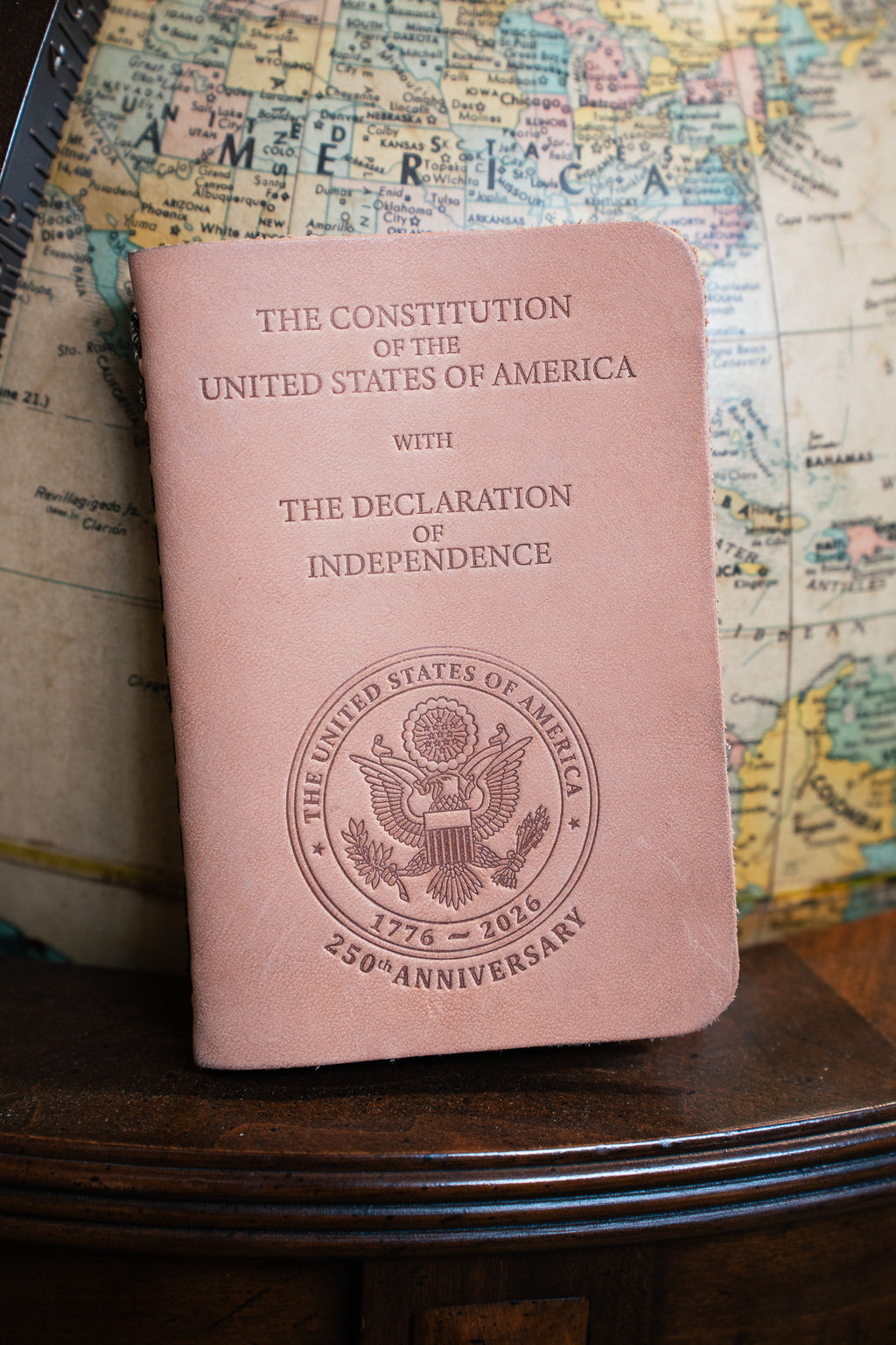 Pocket Declaration/Constitution 250th Limited Edition with embossed anniversary seal, propped against a globe