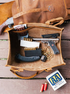 Range and Tool Tote in Tobacco open on a wooden deck, holding a pistol, a magazine and boxes of ammunition