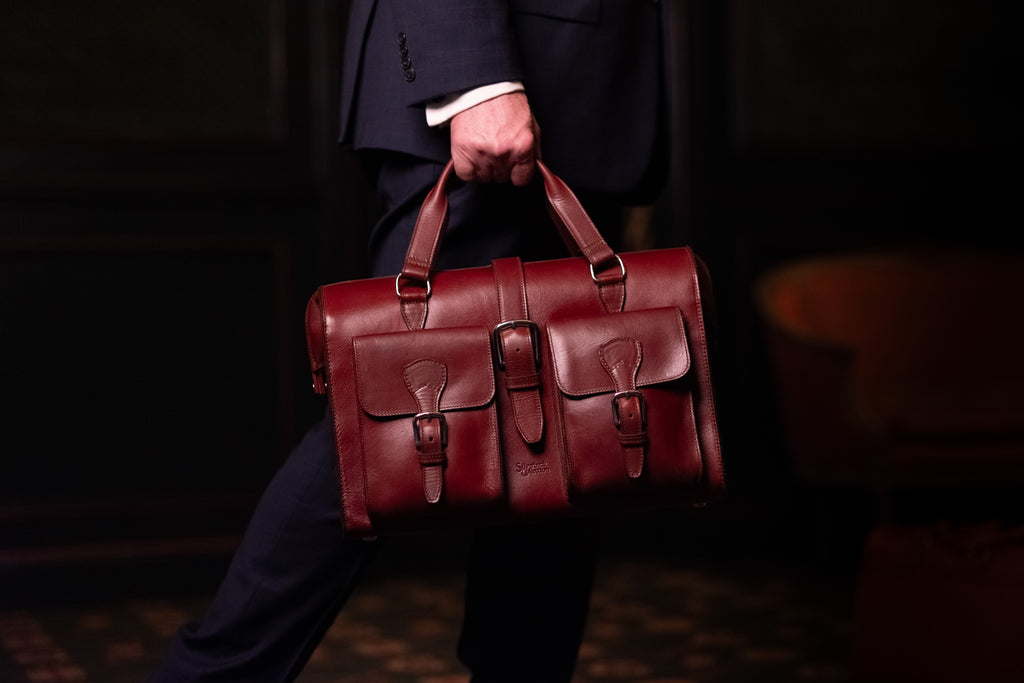 Blackstone Barrister Briefcase in Oxblood carried in mid-stride by a man in a suit in a dim room