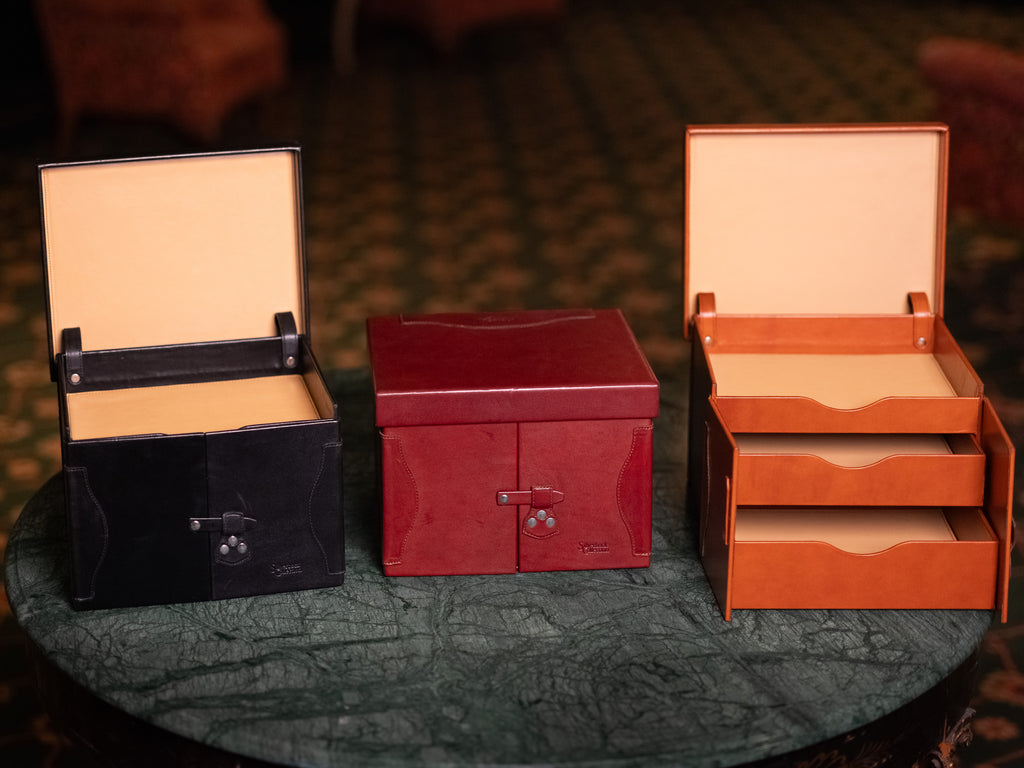 Churchill Case in Raven Black, Oxblood and English Tan side by side on a marble table, two shown open