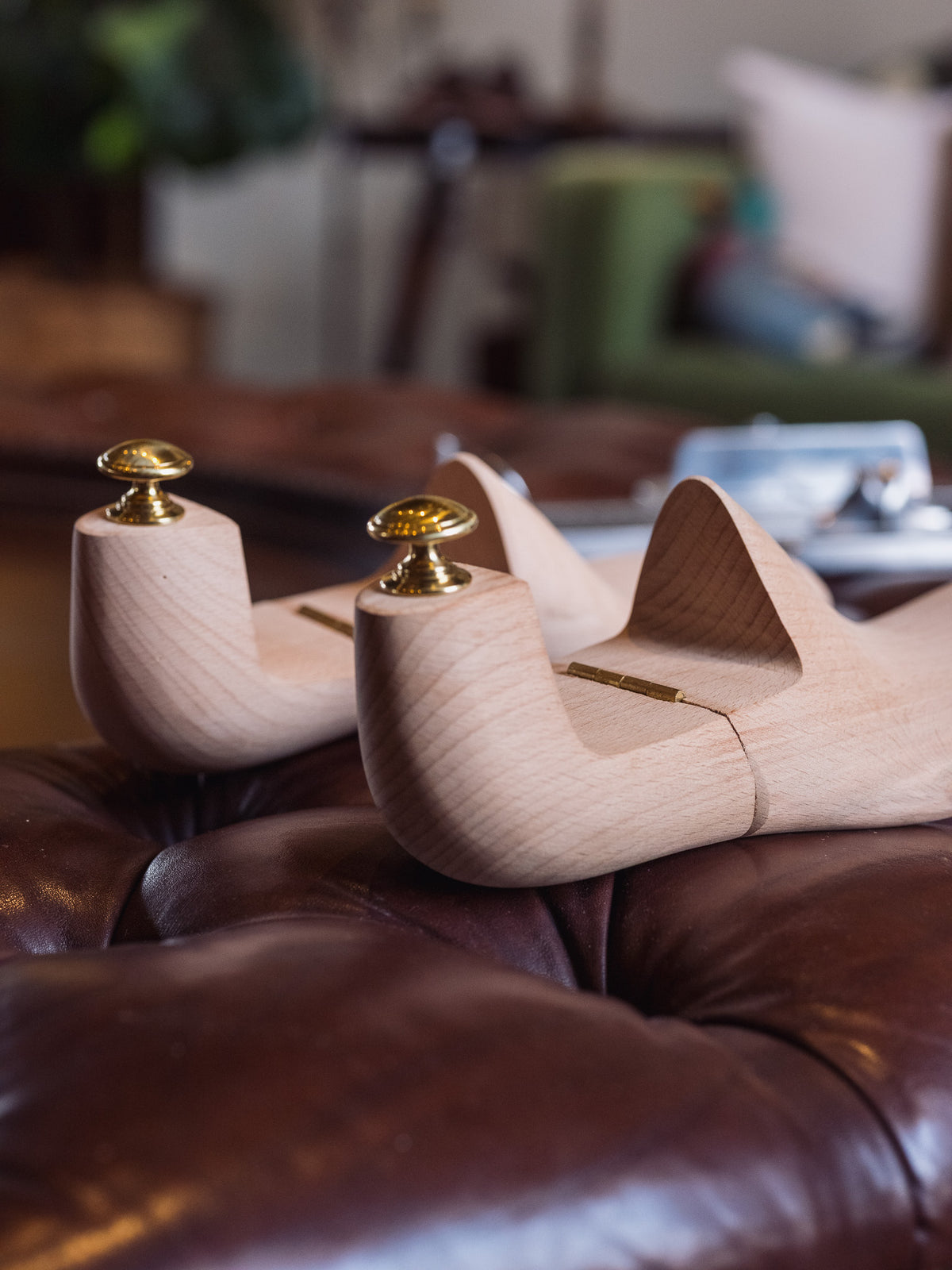 Shoe Tree pair, close-up of the brass knobs and heel blocks on a tufted leather ottoman