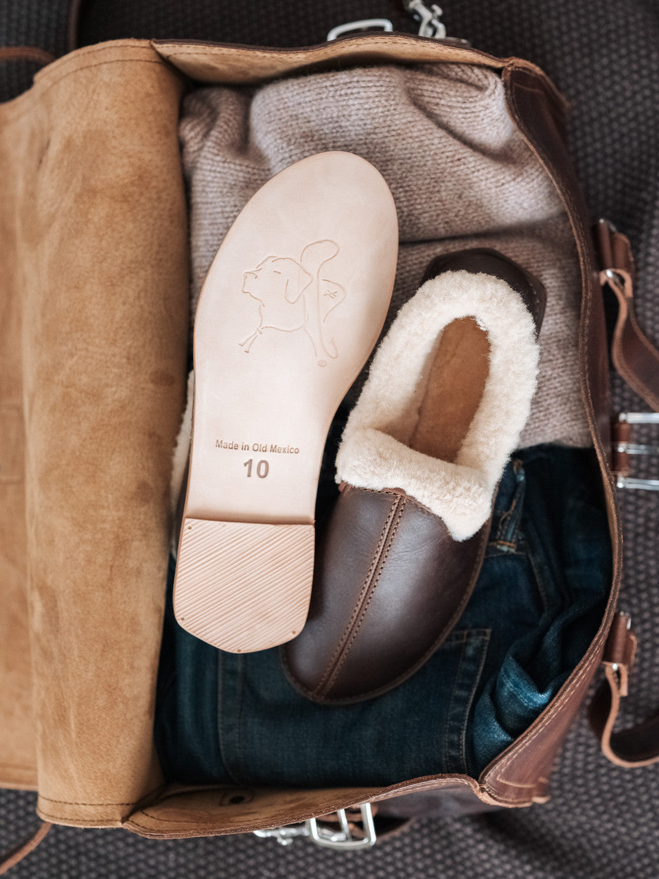 Sheepskin Moccasins in Dark Coffee Brown packed in a leather bag, showing the sole and fleece lining