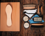 Luxury Shoe Shine Kit top view, wooden shine box with foot rest beside brushes, cream tins, leather care bottle and cloths