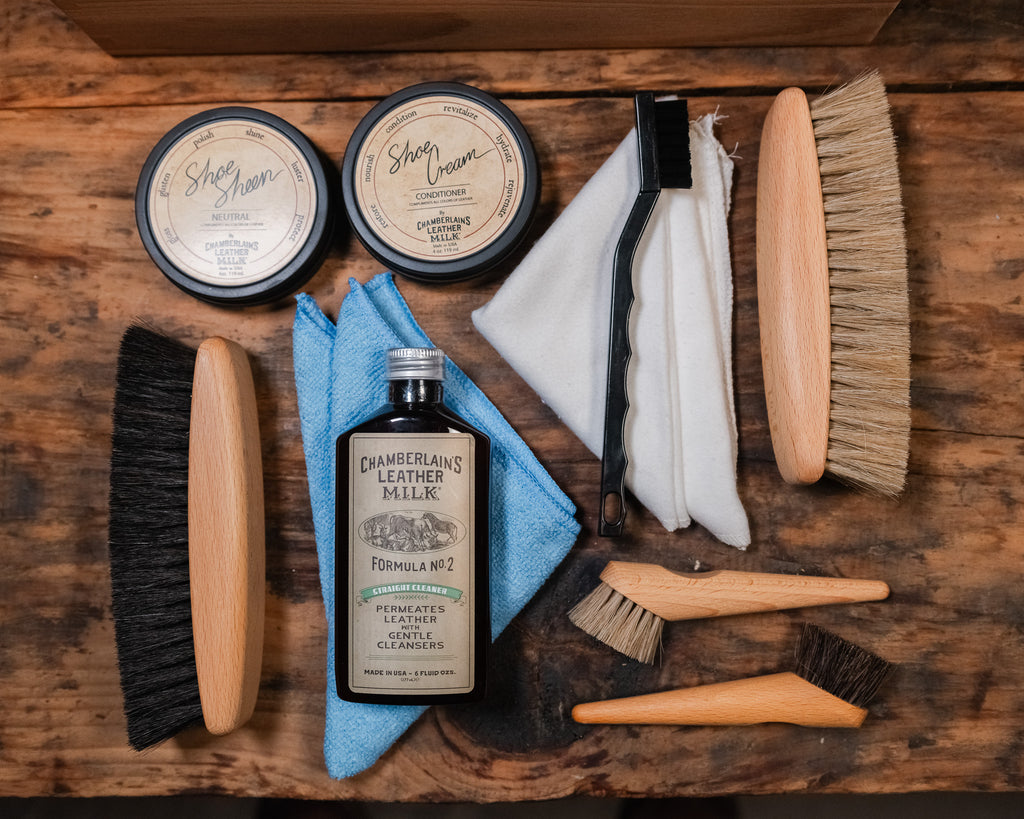 Luxury Shoe Shine Kit laid out on wood with two shoe cream tins, leather care bottle, horsehair brushes, daubers and cloths