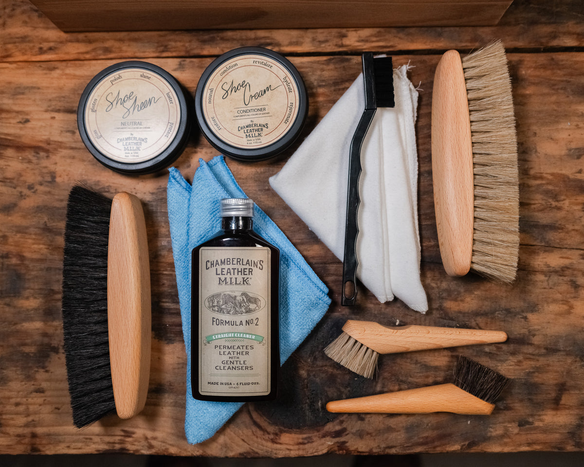 Luxury Shoe Shine Kit laid out on wood with two shoe cream tins, leather care bottle, horsehair brushes, daubers and cloths
