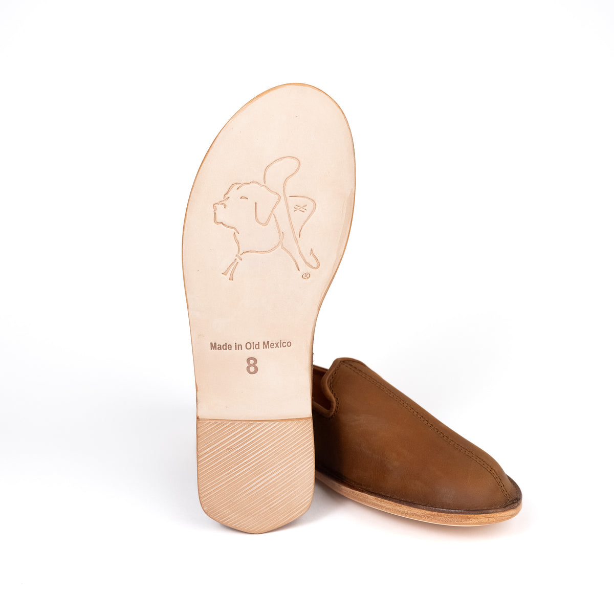 Barefoot Slip-on Shoe in Tobacco beside a leather sole showing the embossed bulldog logo and size stamp