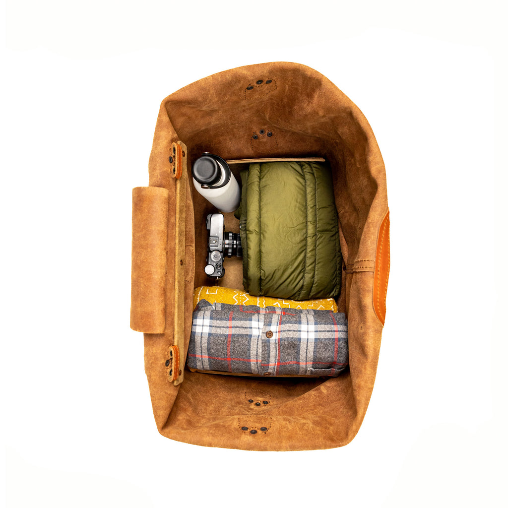 20" Waterbag in Clay, top-down view packed with a jacket, flannel blanket, bottle and camera