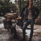 24" Waterbag in brown, strapped to a loaded adventure motorcycle beside its rider on a forest trail