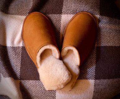 Pair of Women's Sheepskin Slippers in Tobacco on a checkered blanket, top view