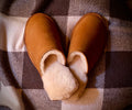 Women's Sheepskin Slippers in Tobacco, top view on a plaid blanket