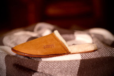 Women's Sheepskin Slipper in Tobacco resting on a checkered blanket, side view