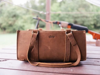Brown leather Tool Tote on a wooden table with a blurred outdoor background