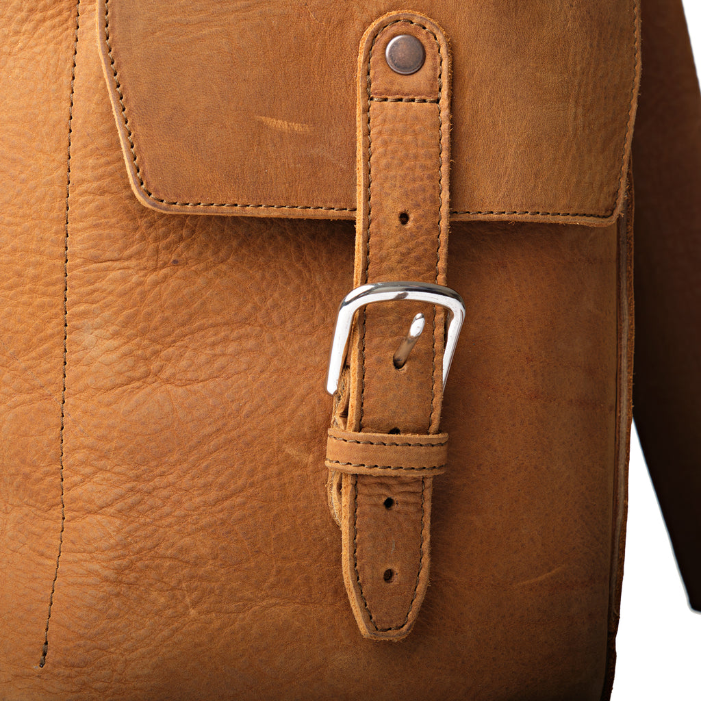 16" Drawstring Backpack in Tobacco, close-up of side pocket strap and buckle on tumbled leather