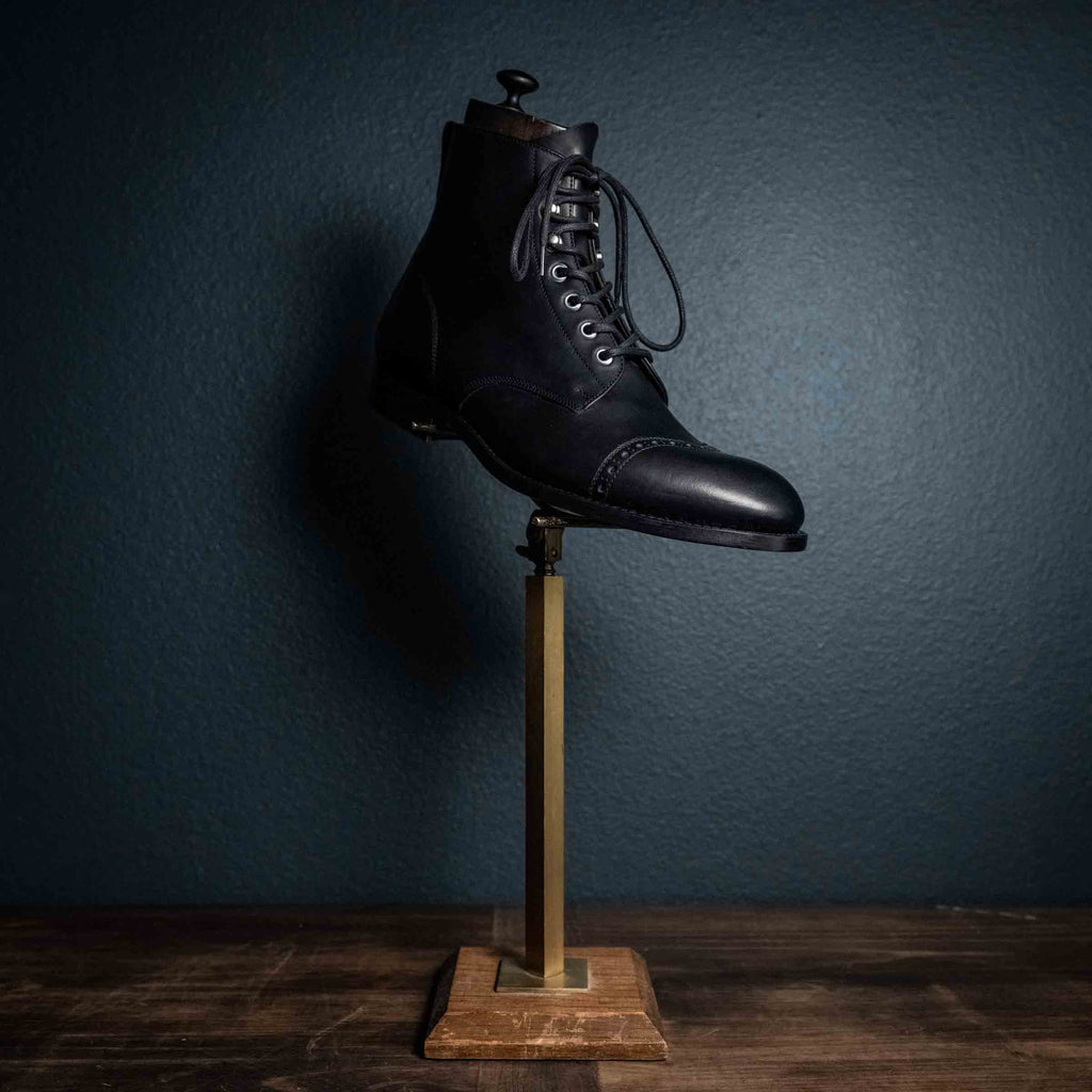 Officer's Boot in Raven Black, single boot displayed on a brass stand