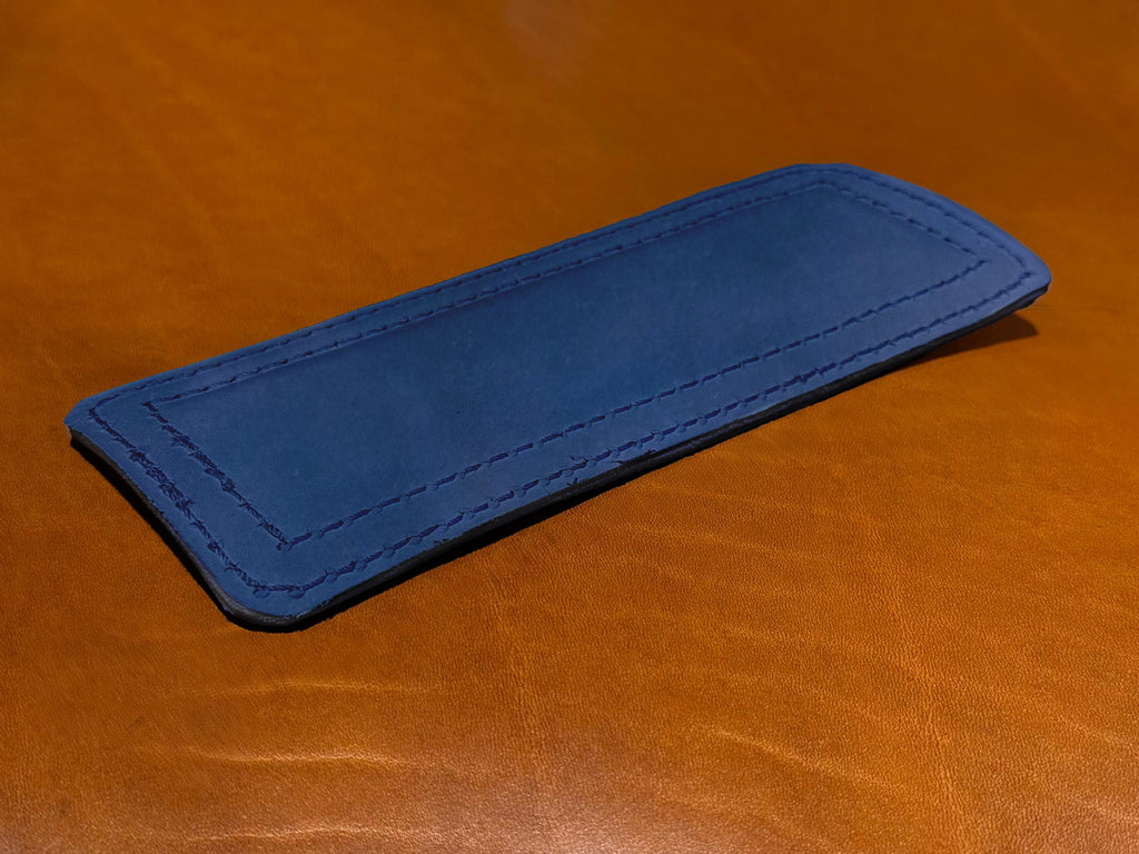 Freedom Collection Extra Shoulder Pad in Blue, lying on a tan leather surface