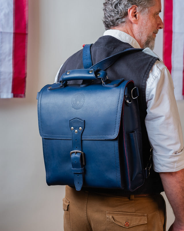 A man wearing the messenger bag as a backpack, seen from behind