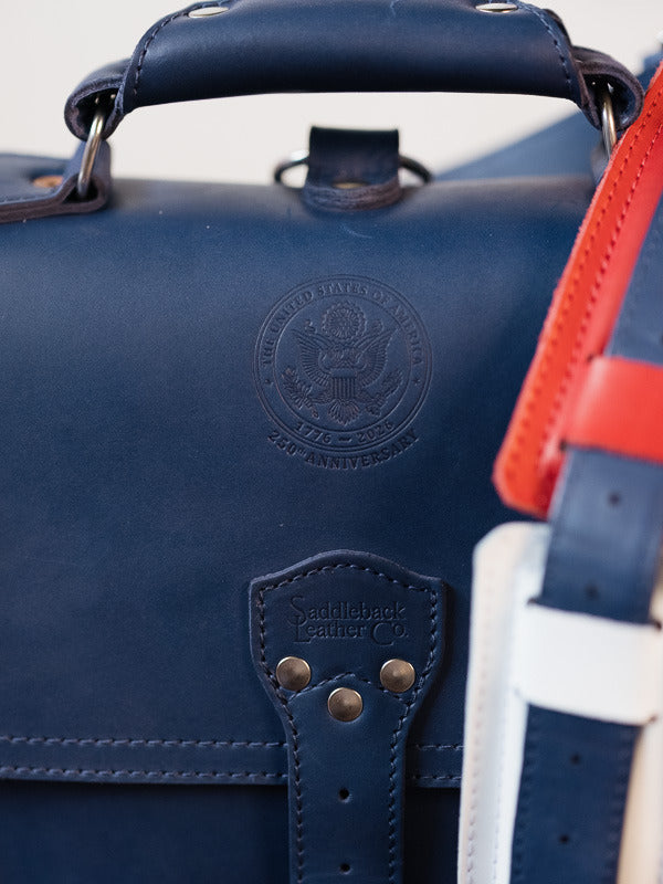Close-up of the embossed seal on the navy bag, beside its red and white strap