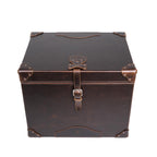Leather Small Trunk in Dark Coffee Brown, closed front view from above showing lid, embossed logo patch and buckled strap