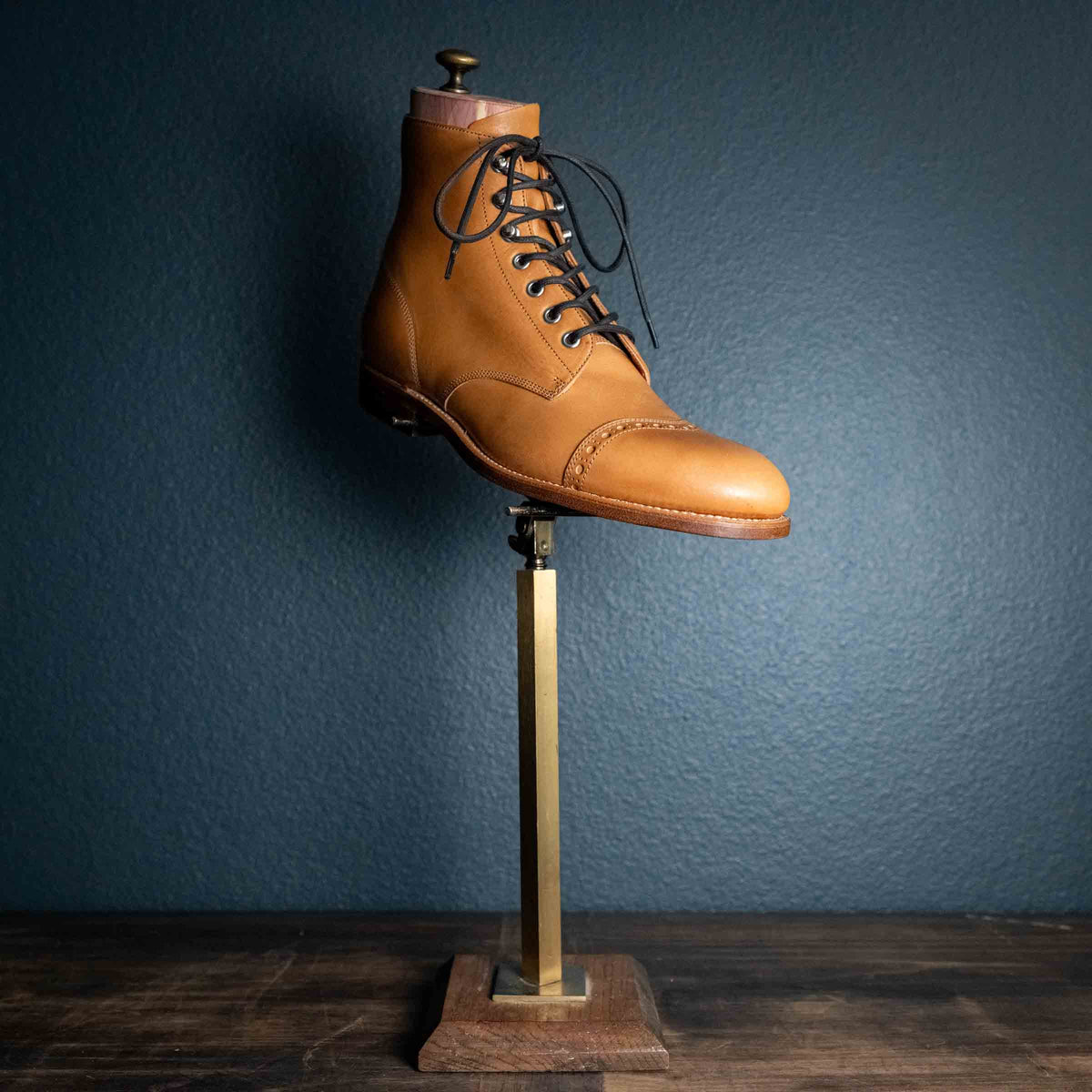 Officer's Boot in English Tan, single boot with dark laces displayed on a brass stand