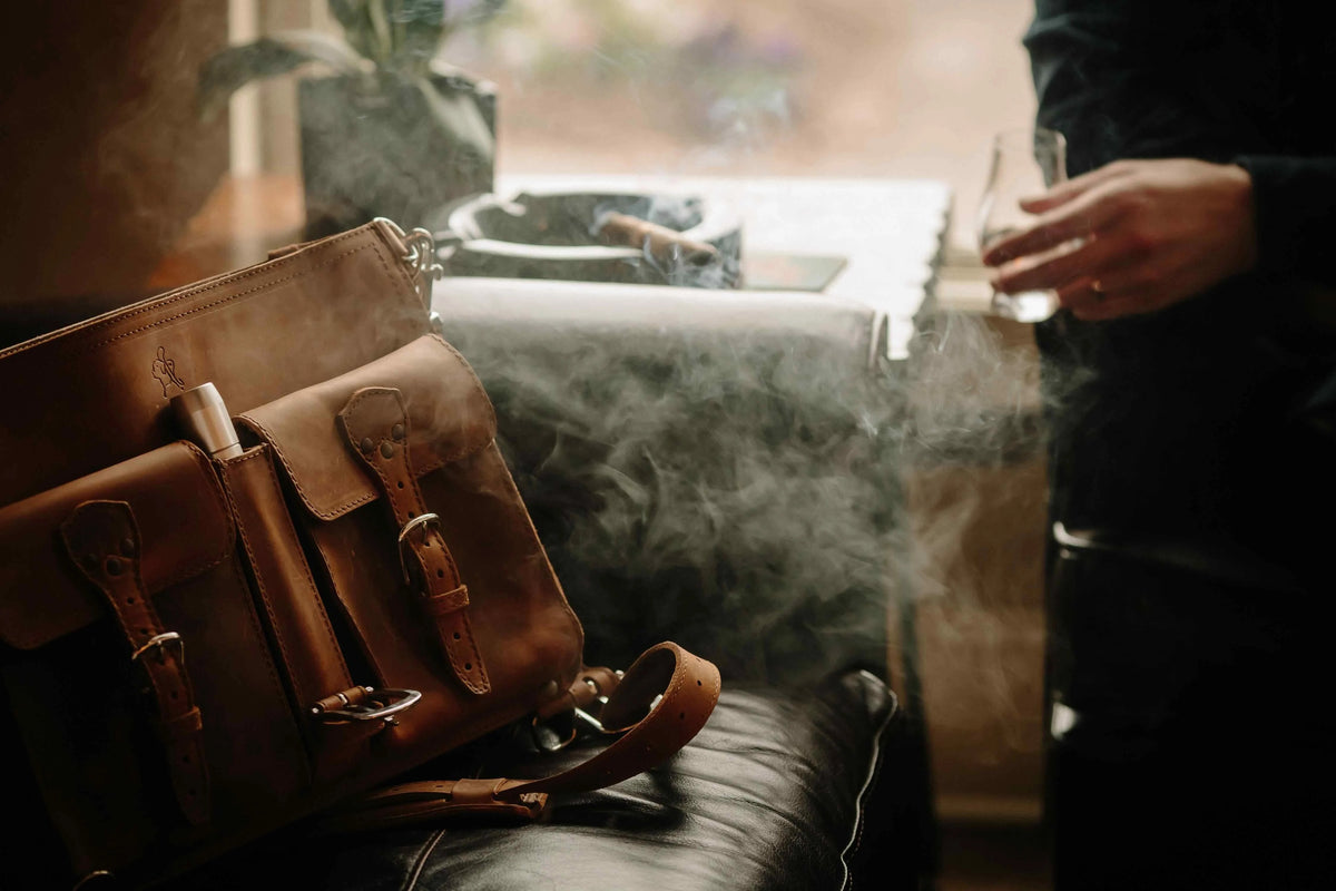 Brown Front Pocket Leather Briefcase on a leather chair with a cigar in the front pocket and smoke in the air