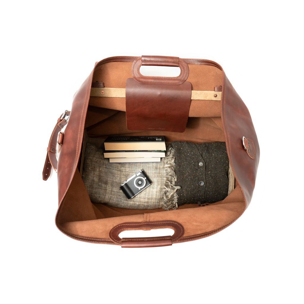 24" Waterbag in reddish brown, top-down view inside packed with blankets, books and a camera