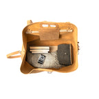 24" Waterbag in tan, top-down view inside packed with blankets, books and a camera