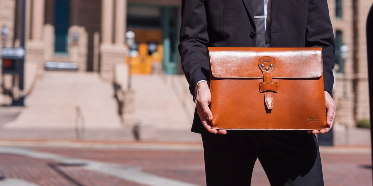 Silverback Document Holder in English Tan held in front by a man in a dark suit outside a stone building