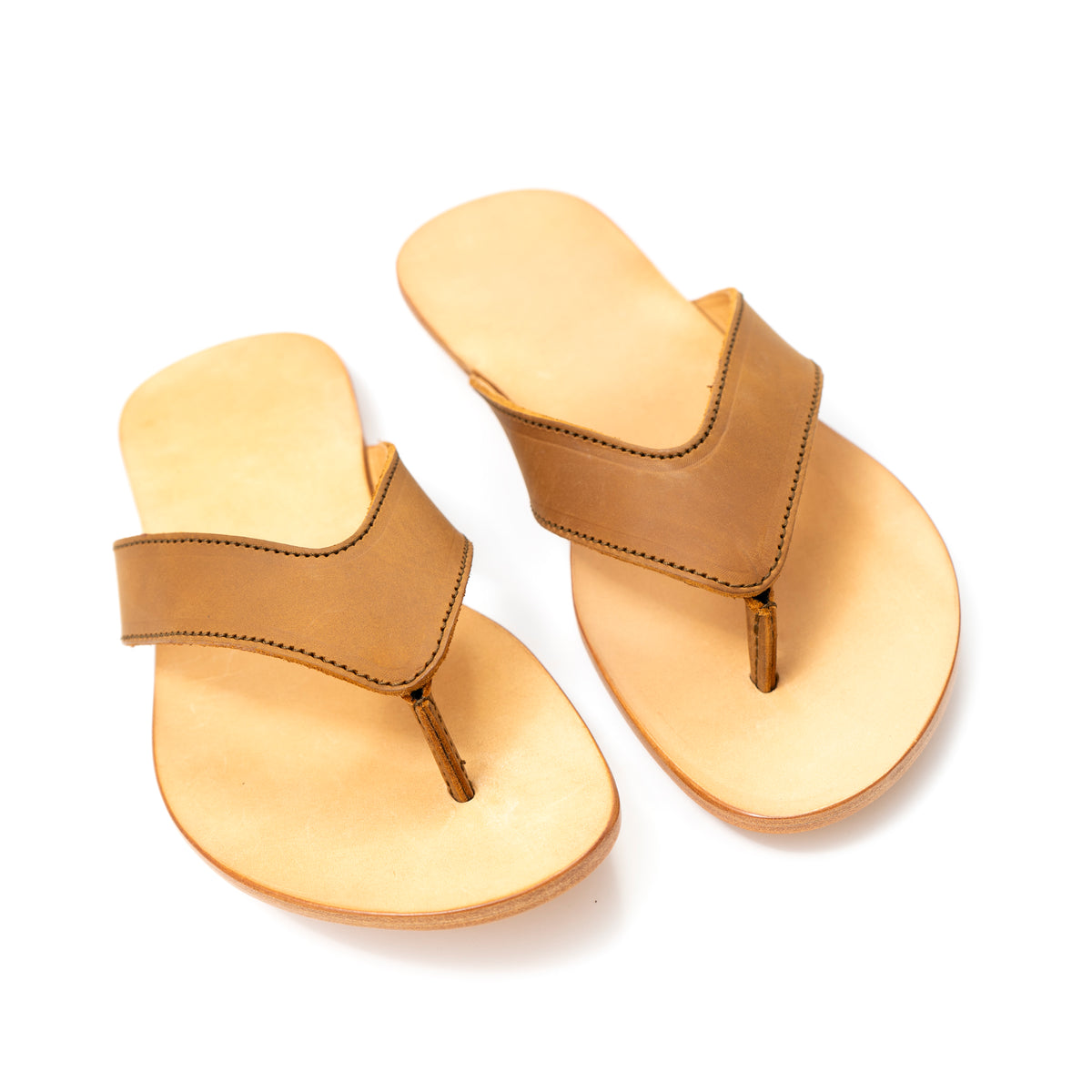 Pair of Flip Flops in Tobacco leather with V-shaped thong straps and natural footbeds, front angled view