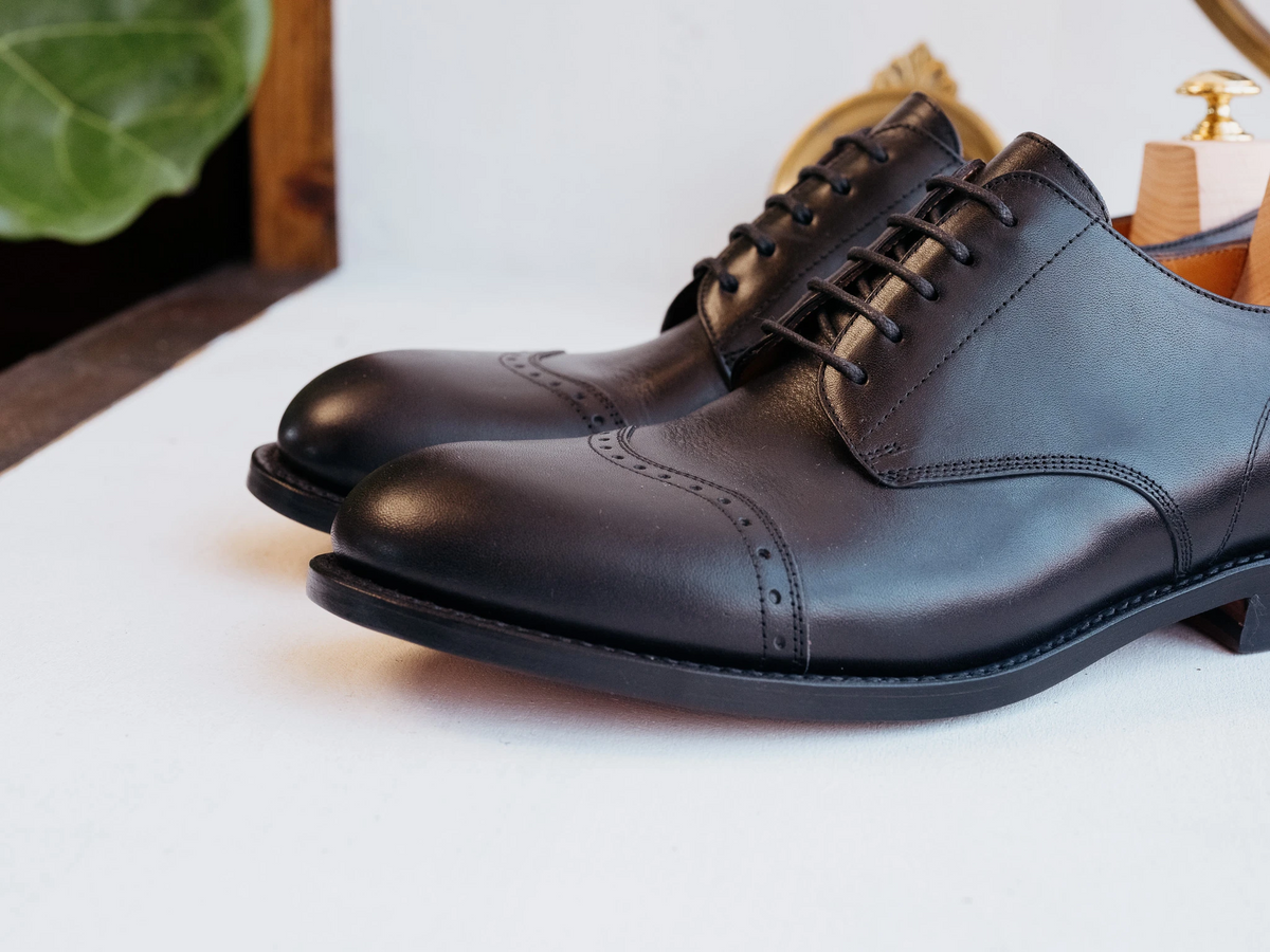 Toe Cap Shoes - Raven Black, low side view of a pair showing the brogued cap toe and leather welt