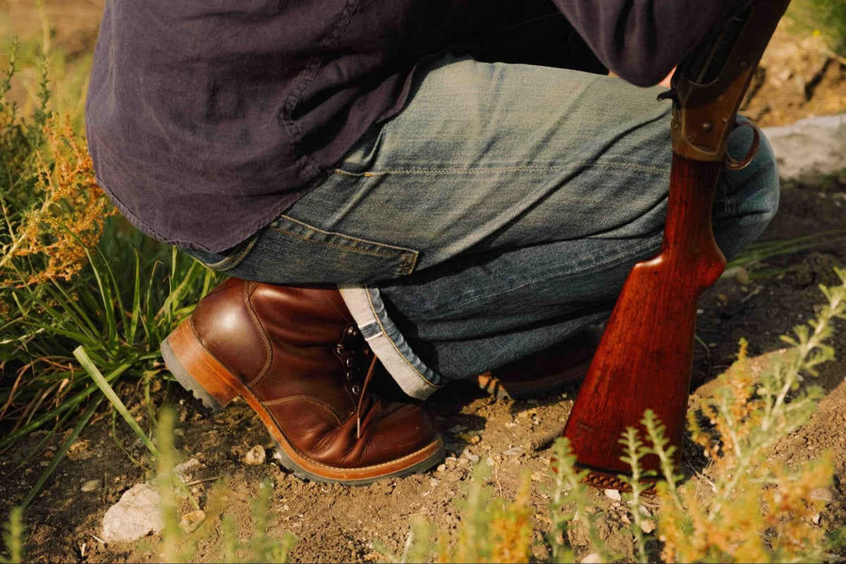 Huntsman Boots - Dark Coffee Brown on a person in jeans crouching in a sunlit grassy field